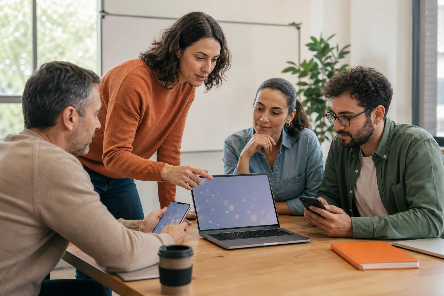 Formadora y alumnado adulto trabajando con dispositivos digitales en un aula.
